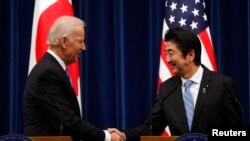 美国副总统拜登(左)和日本首相安倍晋三12月3日在东京举行联合记者会后握手。
