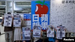 香港苹果日报员工手持最后一起报刊在公司标志旁留影。(2021年6月24日)