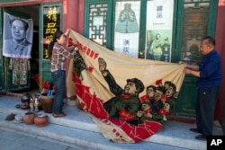 北京旧货市场上的1969年的文革横幅画布,上面有戴红卫兵袖章的毛泽东、其他文革领导人林彪、江青和周恩来以及红卫兵。横幅上写着“大海航行靠舵手” 和“毛主席检阅文化革命大军”(2016年5月16日)