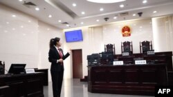 一名中国人民最高法院的工作人员站在法庭内向参观者做介绍。(2018年12月20日)