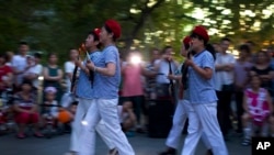 中国妇女在北京一座商城外的广场上随着革命歌曲跳舞,她们手中拿着玩具枪道具。(2014年1月29日)