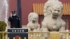 资料照:一名中国警察站在北京天安门前的石狮子旁。(2021年3月11日)