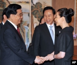 2008年8月25日中国主席胡锦涛和韩国演员李英爱在首尔参加宴会前握手,韩国总统李明博在旁观看
