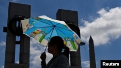 资料照片:一名妇女在高温中参观华盛顿二战纪念碑。(2024年6月19日)