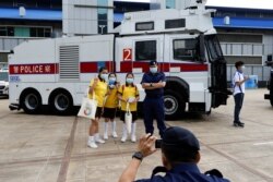 在“全民国家安全教育日“展览当中,小学生在警察水炮车旁边拍照