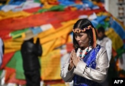 中国西藏自治区首府拉萨的大昭寺外面,一名穿着藏族传统服装的中国游客正在合什拍照(2016年9月10日)。
