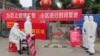身穿防护服的工作人员在武汉一个住宅小区的入口设立登记与体温测量的检查点。(2020年2月13日)