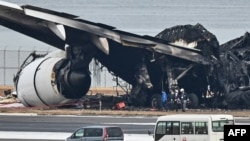 日本官员在羽田机场查看被烧毁的日本航空的空客客机的残骸。(2024年1月3日)