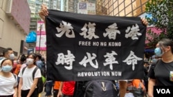 参与5-24港岛反恶法游行的人士高举反送中运动的”光复香港、时代革命”标语,高举这面标语旗帜在港版中国国家安全法实施后,可能会触犯相关法例。 (美国之音汤惠芸拍摄)