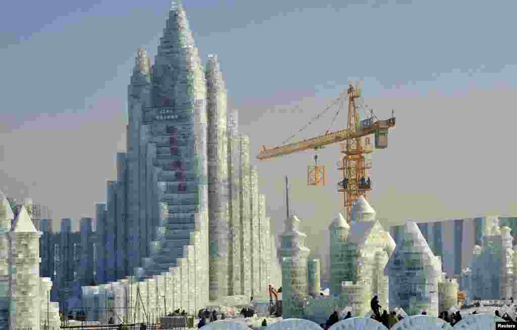 哈尔滨国际冰雪节的冰雕城堡,有工人和起重机在施工(2013年12月27日)