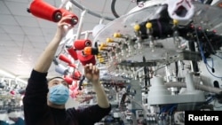 中国浙江湖州一名戴着口罩的工人在生产线上生产出口的袜子。(2020年2月19日)