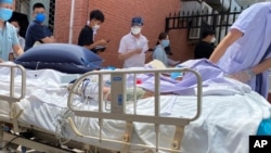 北京一家发热诊所,躺在病床上的病人被推过等待检测的居民队伍。(20020年6月15日)