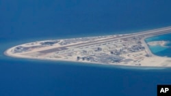 菲律宾空军一架运输机在南中国海南沙群岛的中国造的人造岛礁渚碧礁上空飞越时拍摄的照片,显示人造岛礁上的简易机场和建筑物。(2017年4月21日)