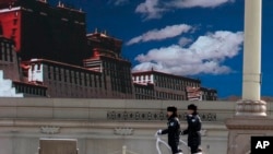 警察在天安门广场巡逻,巨型屏幕上显示着西藏的蓝天白云。(2014年3月9日)