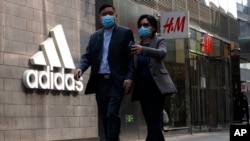 北京市民走过一家商场的阿迪达斯和H&M商店。 (2021年3月25日)