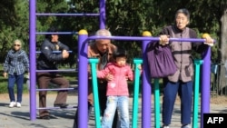 资料照:北京天坛公园里的老年人和他们的独生子女的孙辈在锻炼身体。(2011年10月25日)