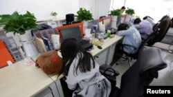 资料照:中国区块链公司Goopal Group在北京的雇员在他们的座位上睡午觉。(2016年4月21日)