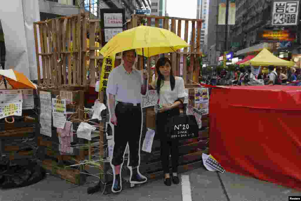 在旺角购物区路障边上与撑开黄雨伞的中国国家主席习近平人像合影