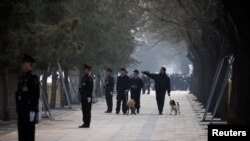 中国武警在即将召开两会的北京人大会堂附近街道上站岗,携带警犬的保安人员在巡逻。(2019年3月3日)