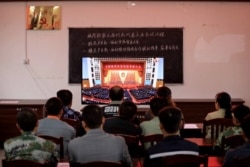 广西柳州一个村庄的村民正在观看在北京人大会堂举行的全国脱贫攻坚总结表彰大会的电视直播。(2021年2月25日)