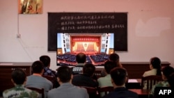 广西柳州一个村庄的村民正在观看在北京人大会堂举行的全国脱贫攻坚总结表彰大会的电视直播。(2021年2月25日)