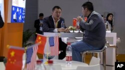 11月6号,进博会上的访问者在一家参展的美国公司展台前面交谈