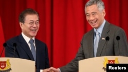 韩国总统文在寅在新加坡总统府与新加坡总理李显龙握手。(2018年7月12日)