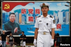 在香港海军基地,一位中国水兵站在一面具有中共党旗、习近平像和香港景象的大型看板前面(2017年7月8日)
