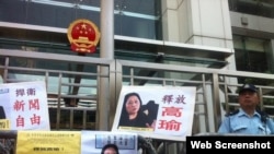 示威者在香港中联办大楼外面放置了要求释放高瑜的标语和图片,旁边是警察(2015年4月17日,网络资料图片)