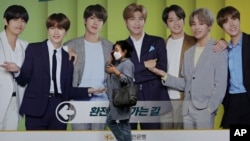 韩国首尔,一名戴着口罩的女子走过一块展示韩国K-Pop组合防弹少年团(BTS)的广告牌(2020年9月30日)。