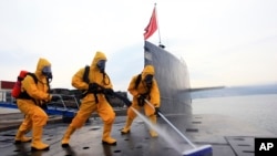 中国海军发布的照片显示,在青岛潜艇基地,穿着防护服的水兵清洁核潜艇。(2013年10月)