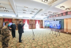 戴着口罩的中国国家主席习近平视察火神山医院时通过视频向新冠病毒感染者和医护人员招手。(2020年3月10日)