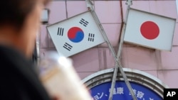资料照:一名女子走过东京街头一家悬挂日韩国旗的商店。(2019年8月2日)