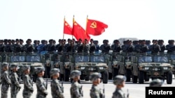 中国解放军军人在内蒙古朱日和训练基地参加阅兵,庆祝解放军建军90周年。中共党旗在前,国旗居中,军旗在后(2017年7月30日)
