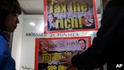香港人在莫萨克·冯赛卡律师事务所的香港地区总部附近示威,举着的标语牌上有习近平等人的像(2016年4月12日)