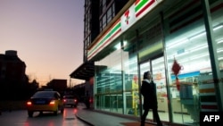 资料照:一名女子走过北京街头一家7-11便利店。(2012年1月3日)