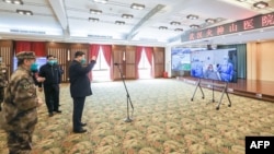 戴着口罩的中国国家主席习近平视察火神山医院时通过视频向新冠病毒感染者和医护人员招手。(2020年3月10日)