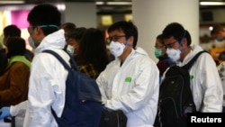 身穿防护服戴着口罩的旅客在德国法兰克福机场的国航柜台前等候办理登机手续。(2020年3月15日)