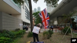 一位民主派支持者于2021年4月16日在香港法庭外挥舞英国国旗。包括82岁的香港民主党创建人李柱铭和支持民主的媒体大亨黎智英在内的七位香港主要的民主派人士因参与2019年8月的一次集会,被控参与未经授权的集结罪名。周五法官对七人做出宣判。