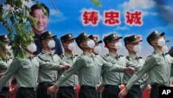 北京街头一队武警士兵走过习近平的宣传画。(2020年5月25日)