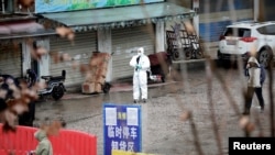 资料照:一名身着防护服的工作人员在被关闭的武汉海鲜市场内。(2020年1月10日)