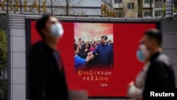 上海街头戴着口罩的行人走过宣传习近平的宣传画。(2020年3月23日)