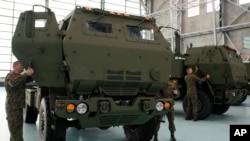 资料照片:波兰士兵在华沙的一个空军基地查看搭载有美国制造的“海马斯”(HIMARS)火箭发射器的军车。(2023年5月15日)