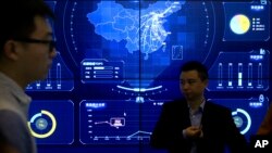 在北京举行的全球移动互联网大会上,参观者站在一个显示中国地图的电子数据显示器前(2018年4月26日)