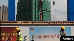 资料照:中国工人从云南省昆明市一处碧桂园开发的建筑工地旁走过。(2019年9月17日)