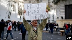 A man holds a sign that reads in Spanish "Macri stop it" during a protest in Plaza de Mayo, Buenos Aires, Argentina, Aug. 22, 2017.