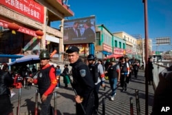 一名中国警察带领一队武装民兵在新疆和田的市场外巡逻。(2017年11月3日)