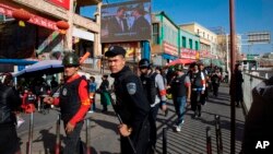 一名中国警察带领一队武装民兵在新疆和田的市场外巡逻。(2017年11月3日)