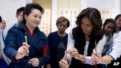 在参观书法课时,习近平夫人彭丽媛教美国第一夫人米歇尔·奥巴马怎样用毛笔写字