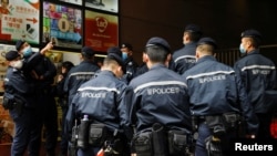 香港警察在逮捕《立场新闻》六名高管后站在该港媒办公楼外。(资料照,2021年12月19日)